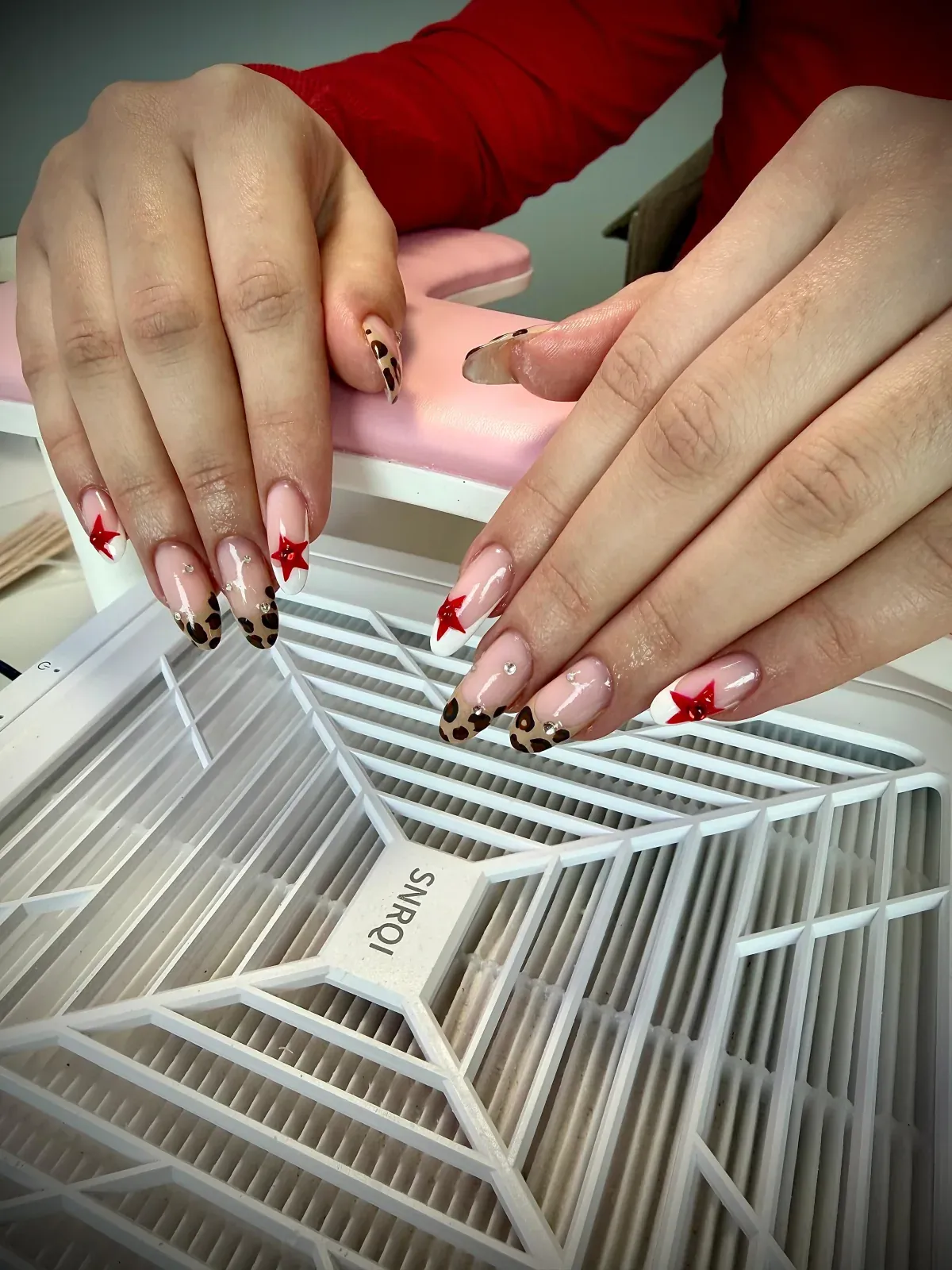 Nude gel nails with leopard French tips and red star accents by Bärli Nails in Neuhausen am Rheinfall