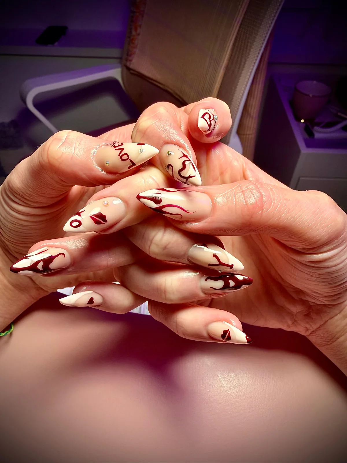 Cream and nude gel nails with burgundy line art and lettering by Bärli Nails in Neuhausen am Rheinfall